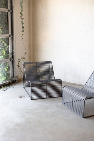 Modern metal chairs in a minimalistic room with a window and plant.