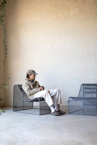 Person sitting on a modern chair in a minimalistic room with a plant.