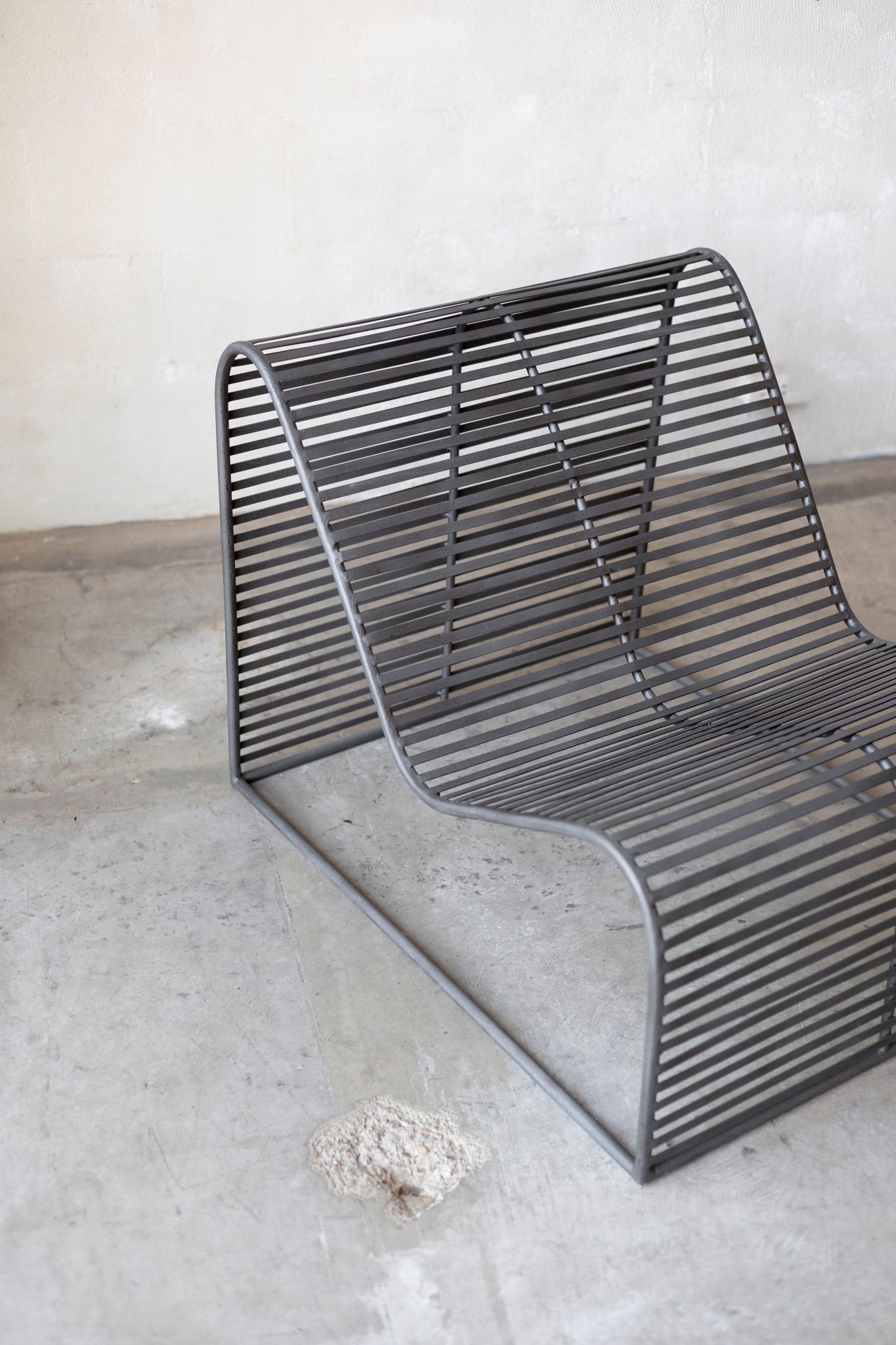 Modern metal chair on a concrete floor with a neutral background