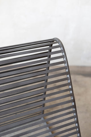 Close-up of a metal chair with a curved backrest on a plain background