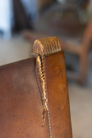 Close-up of a brown leather chair back with a worn seam.