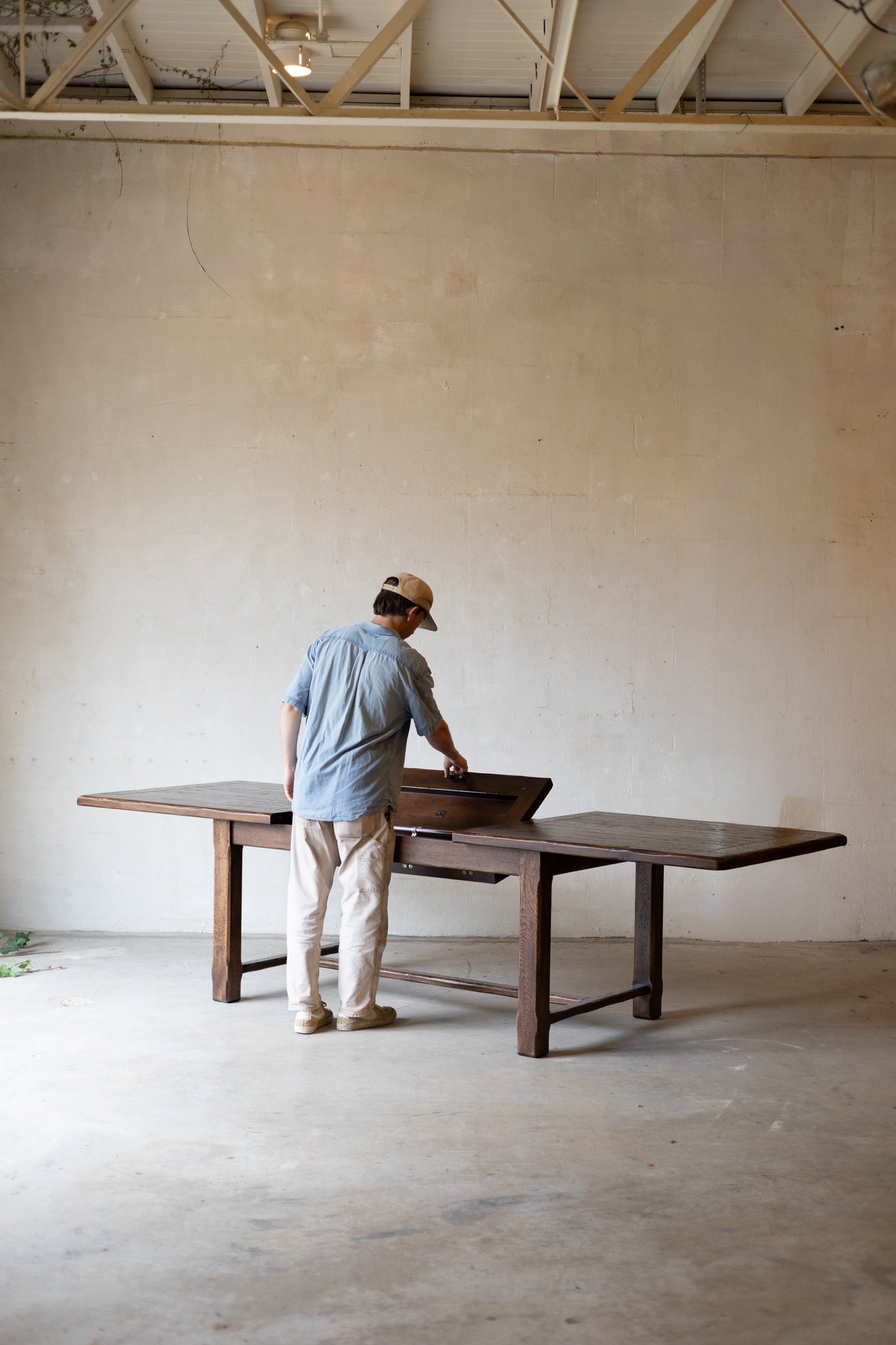 long dark wood dining table in a minimalist room with a concrete floor and plaster wall.