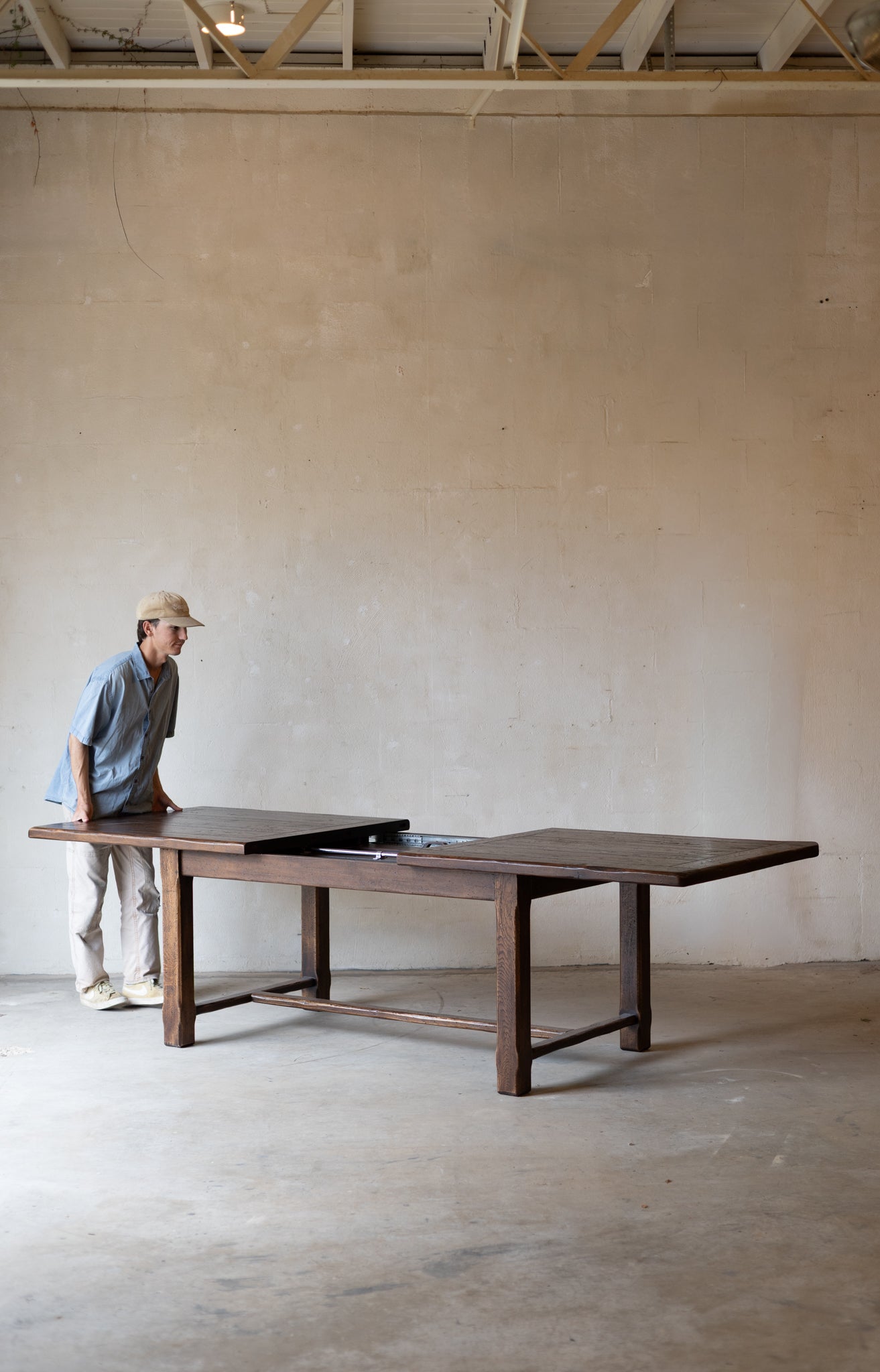 large dark wood dining table in a minimalist room with a concrete floor and plaster wall.