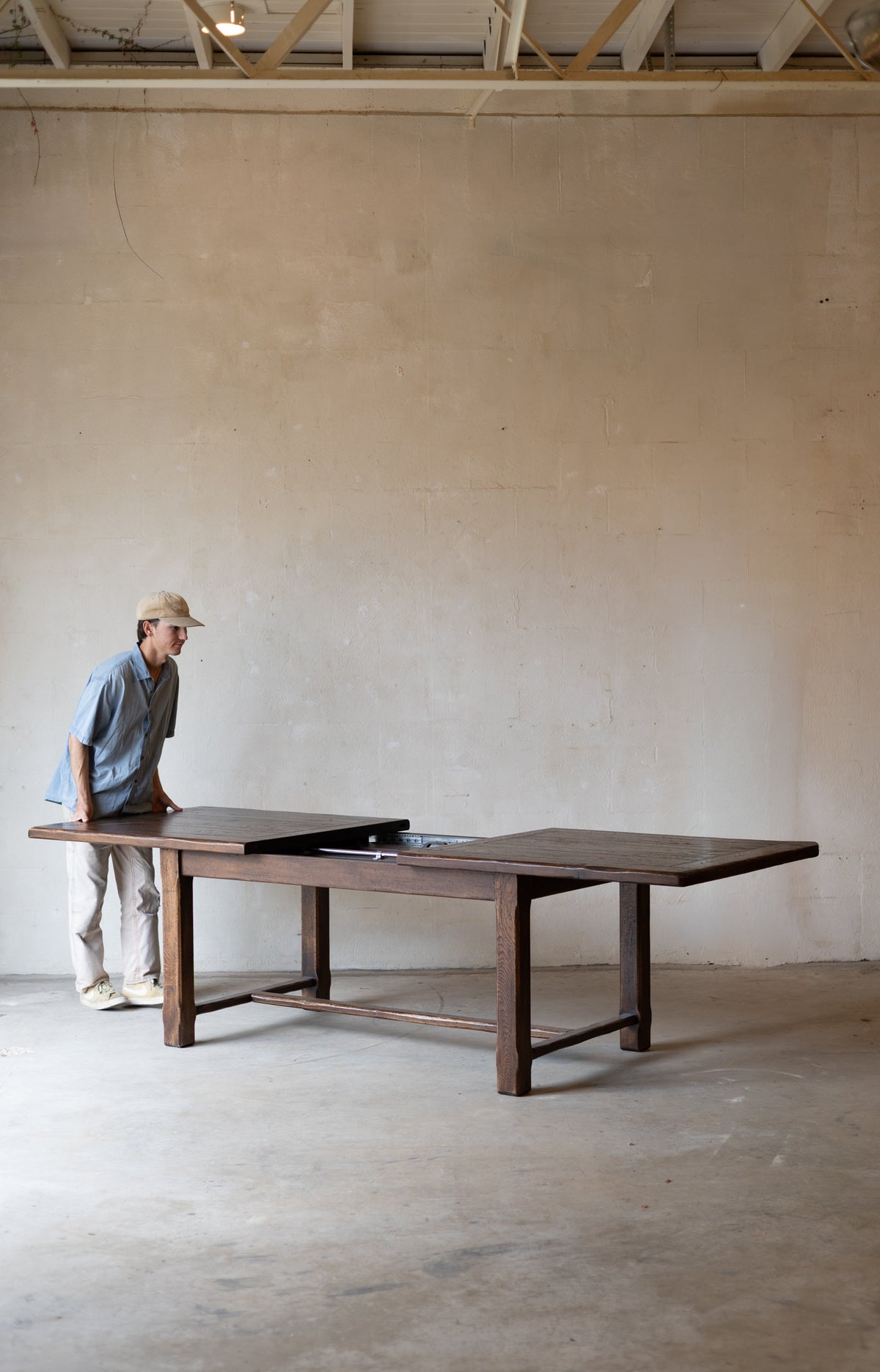 large dark wood dining table in a minimalist room with a concrete floor and plaster wall.