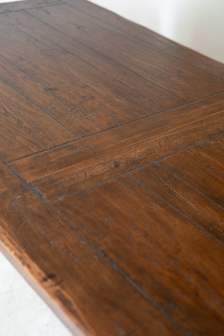 Close-up of a dark brown wooden table showing the wood grain and panel construction.