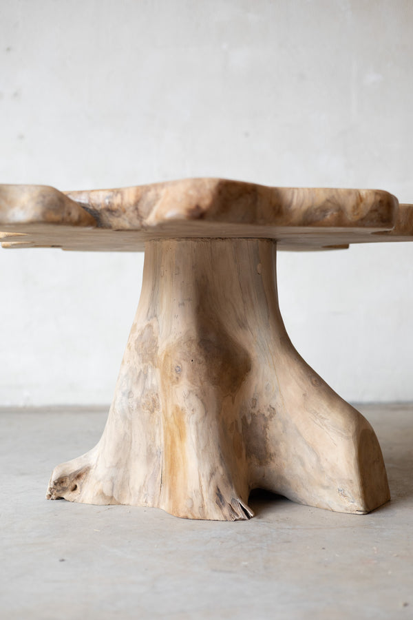 Wooden table with a natural, tree-stump-like base on a plain background