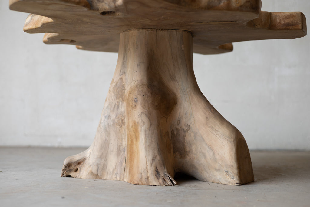 Wooden table with a natural, tree-stump-like base on a plain background