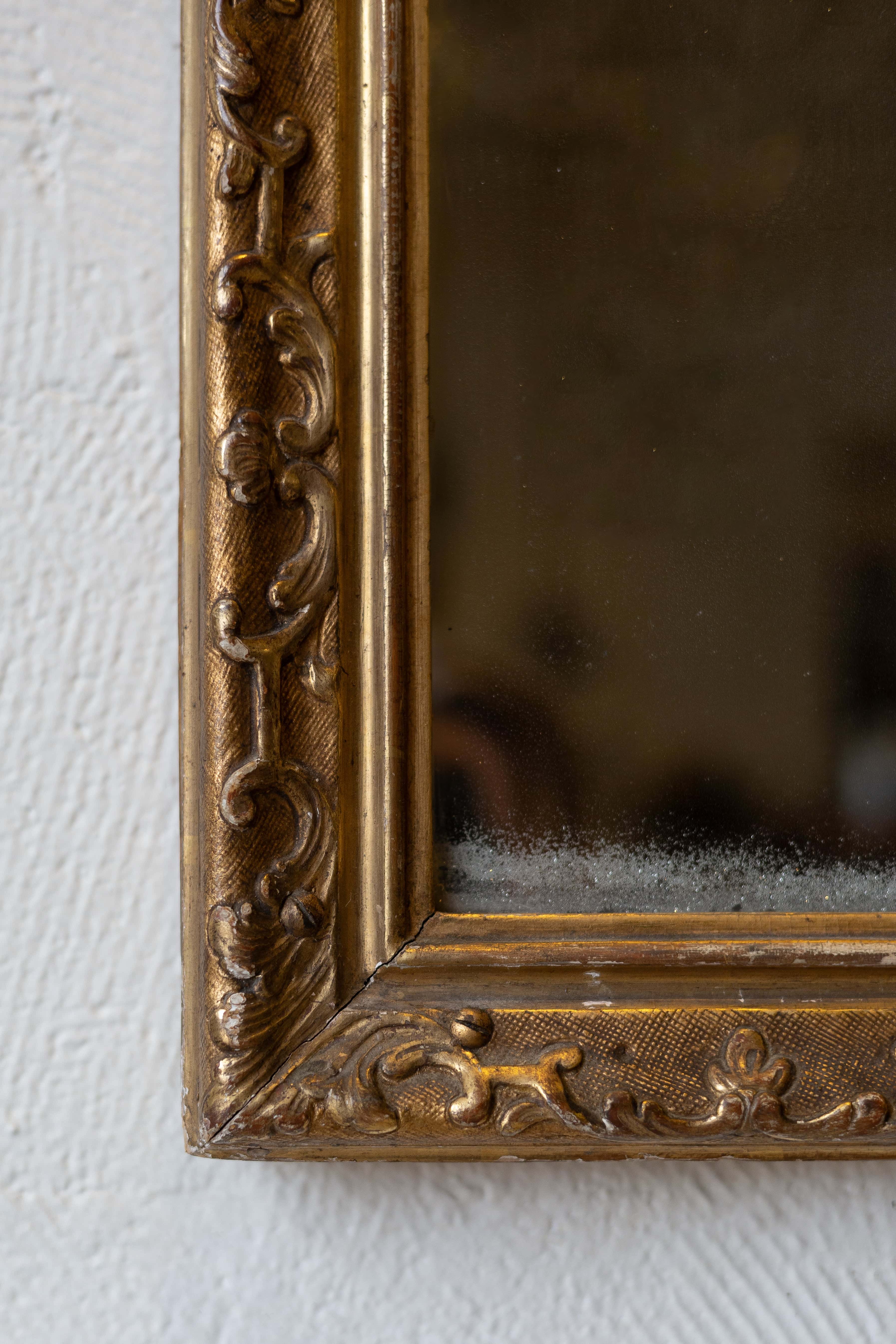 Close-up of an antique mirror's baroque gold frame design. 