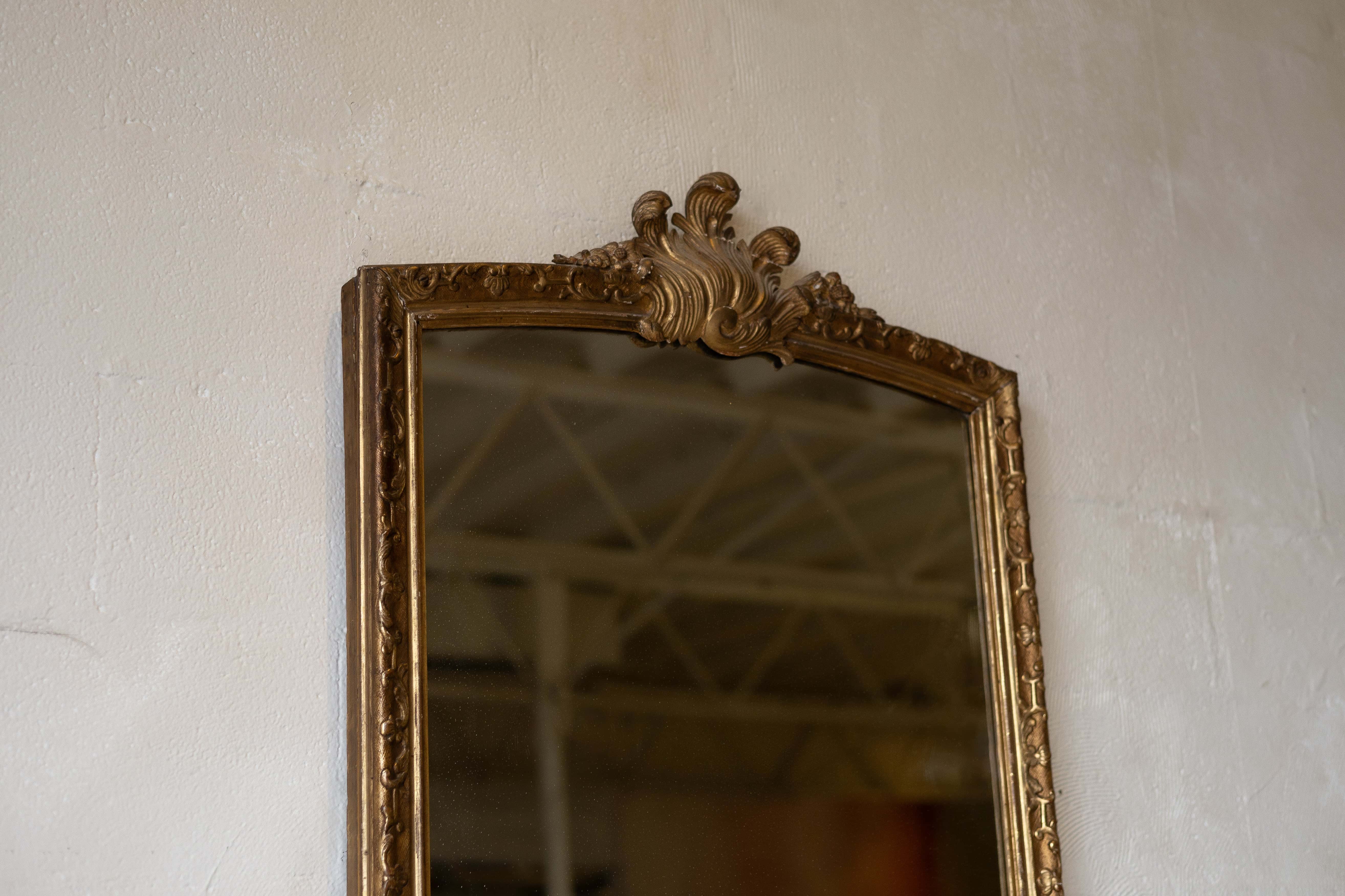 Partial image of an antique split glass mirror with a baroque frame and acanthus ornament.
