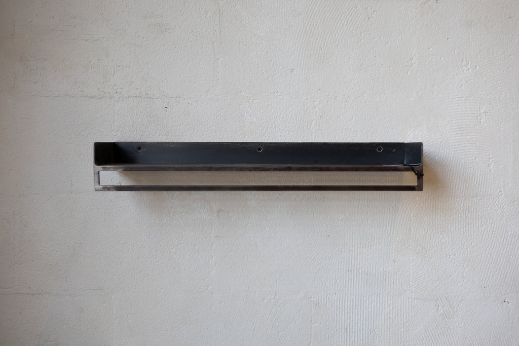 Black rectangular shelf on a textured white background.