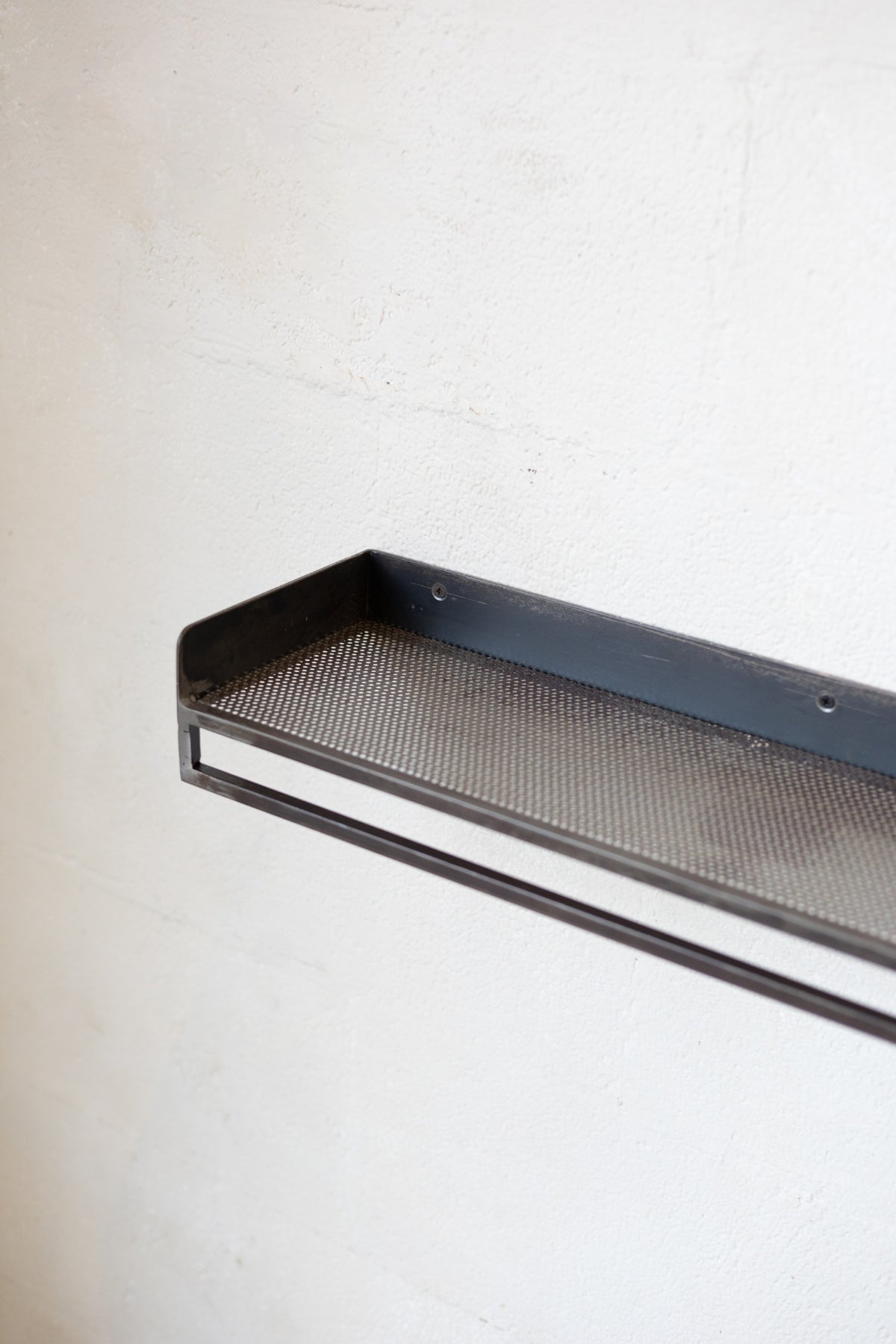 Black metal shelf with mesh design on a white background.