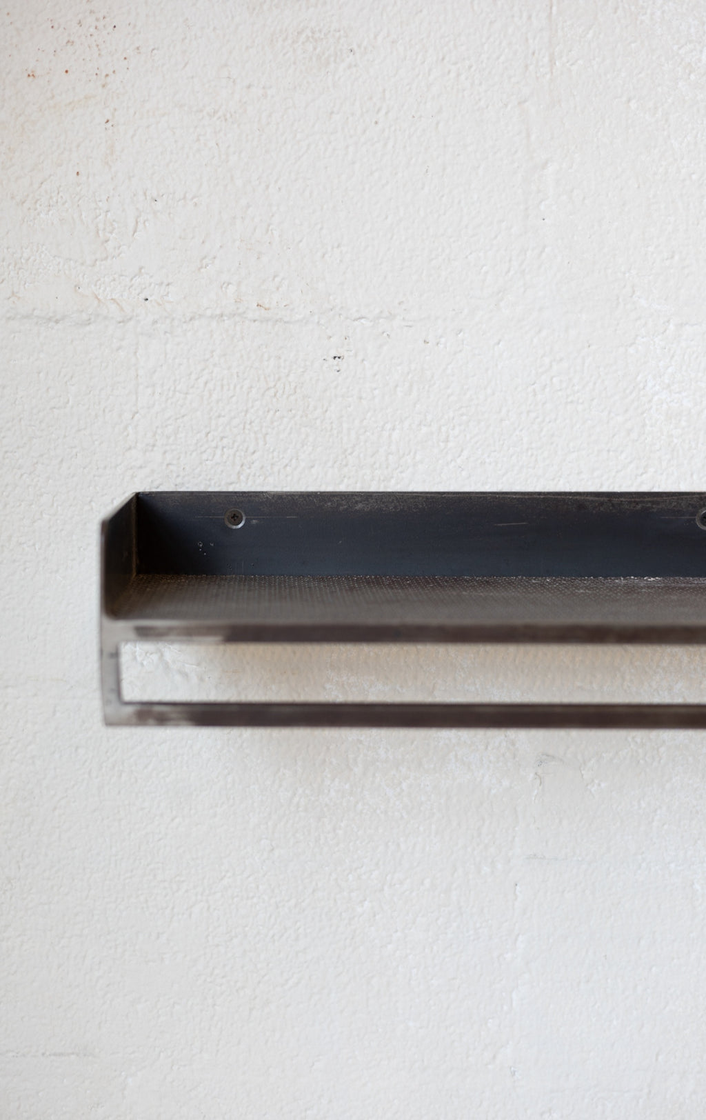Metal rectangular shelf on a textured white background.