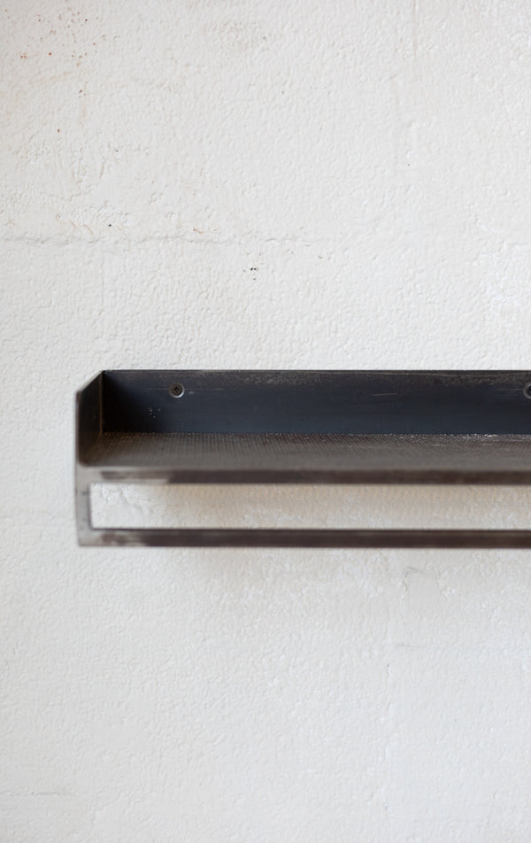 Metal rectangular shelf on a textured white background.