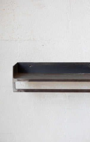 Metal rectangular shelf on a textured white background.