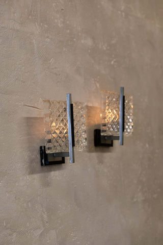 Staggered pair of vintage wall sconce featuring a prism glass shade with a diamond pattern and sleek metal frame with a minimalist design.