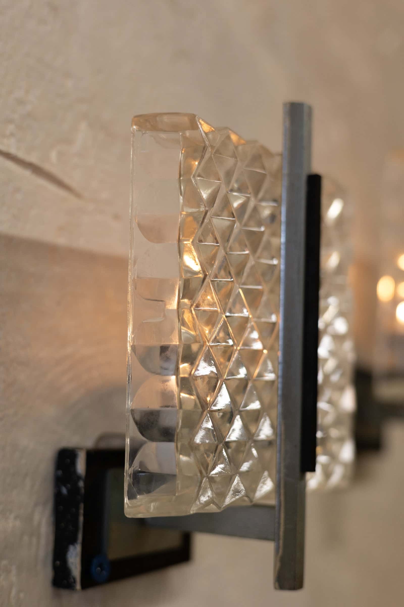 Side angle view of vintage wall sconce featuring a prism glass shade with a diamond pattern and sleek metal frame with a minimalist design.