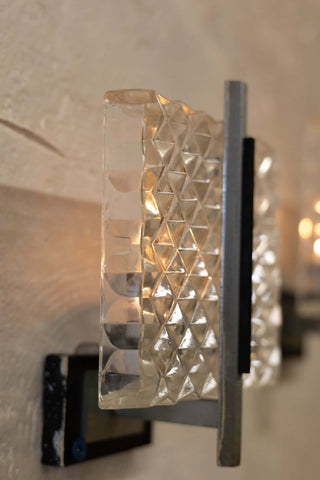 Side angle view of vintage wall sconce featuring a prism glass shade with a diamond pattern and sleek metal frame with a minimalist design.