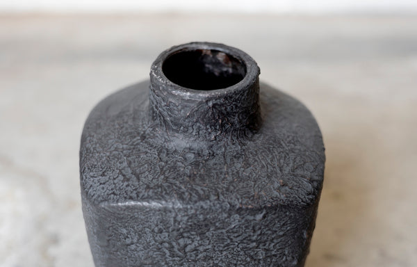 Textured black ceramic bottle on a light background