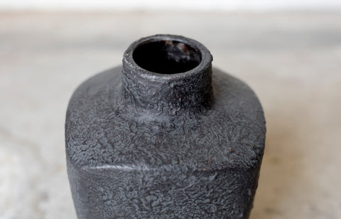 Textured black ceramic bottle on a light background