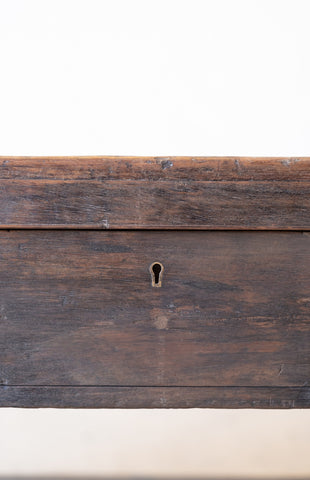 Close up of keyhole of storage compartment of vintage teak wood coffee table with an iron handle on a neutral background.