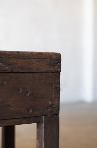 Close up of the corner of vintage teak wood coffee table on a neutral background.