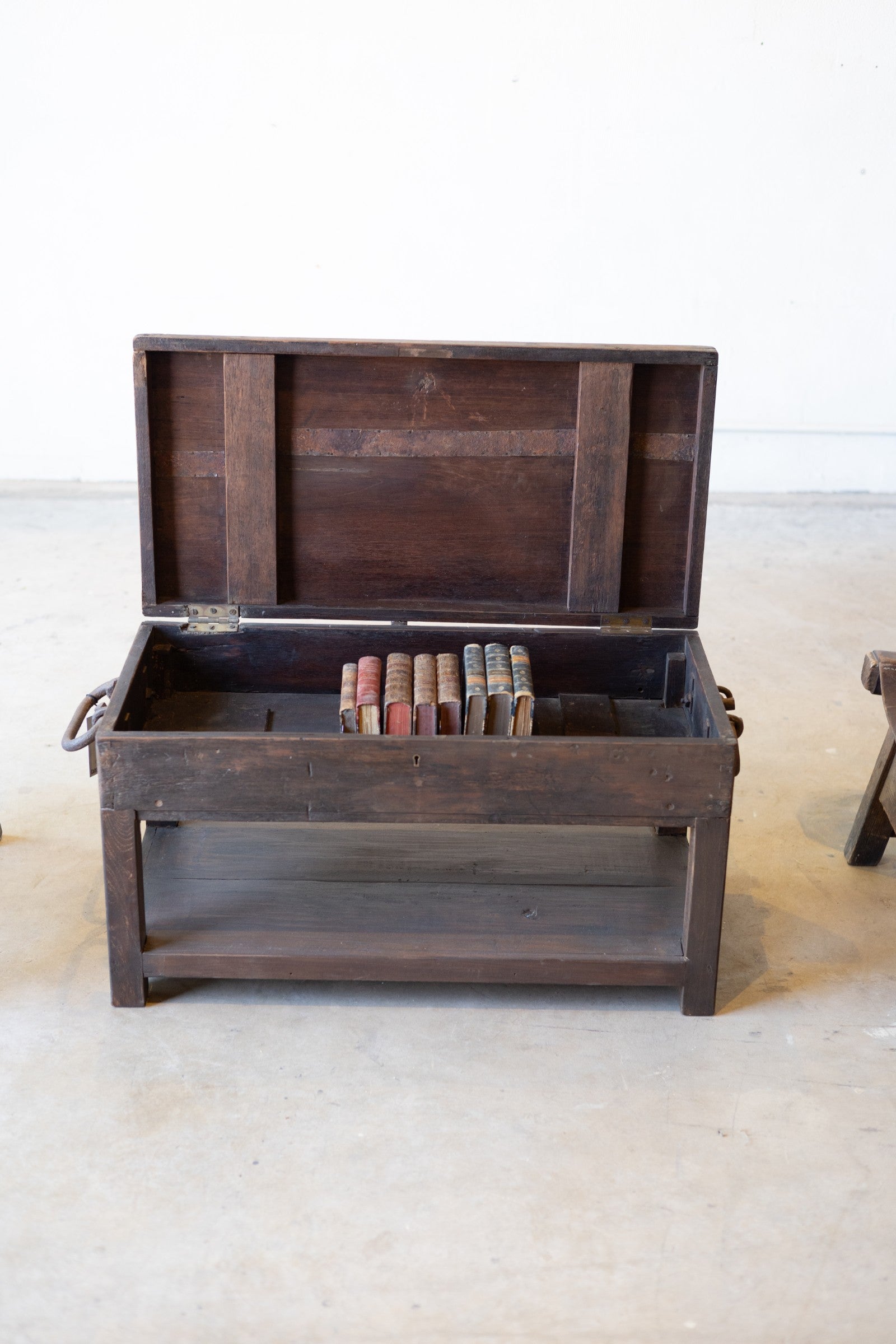 Vintage wooden coffee table featuring an opening top with books inside on a white background.