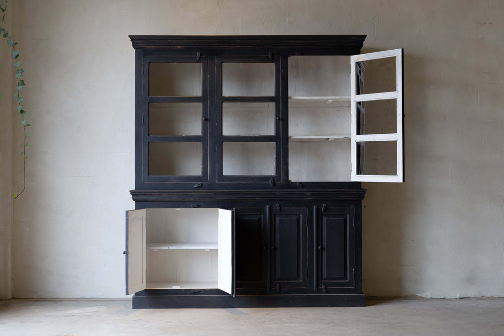 Black wooden hutch with one open glass door and one open cabinet, revealing white interior. 