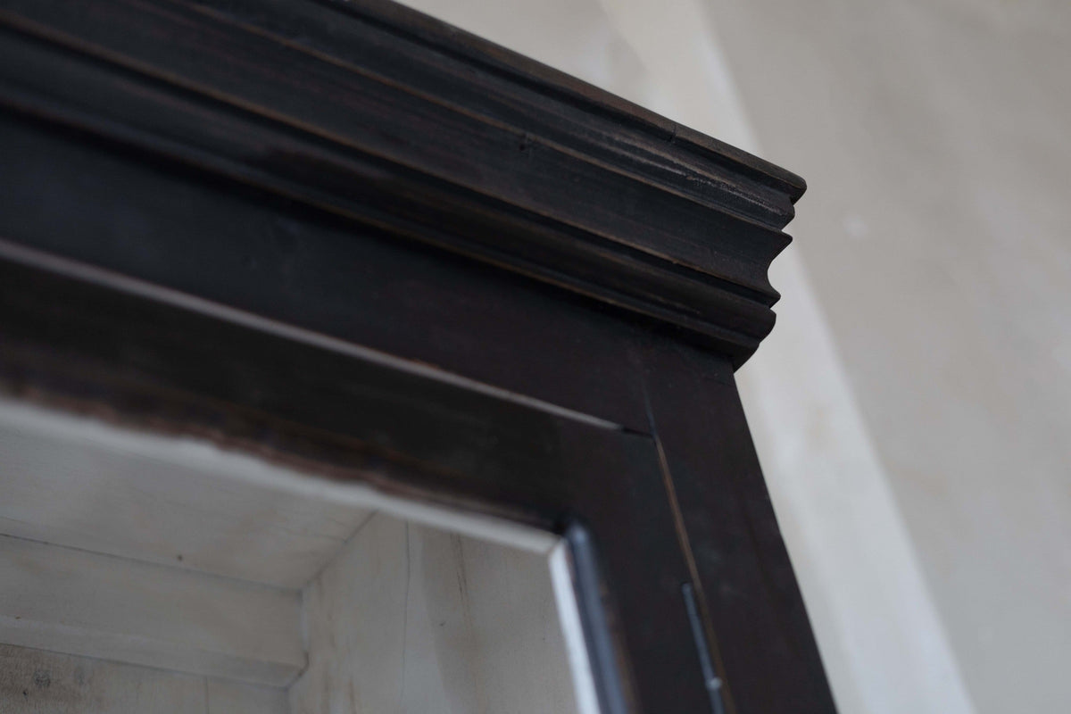 Close-up of wooden black hutch, showing crown moulding.