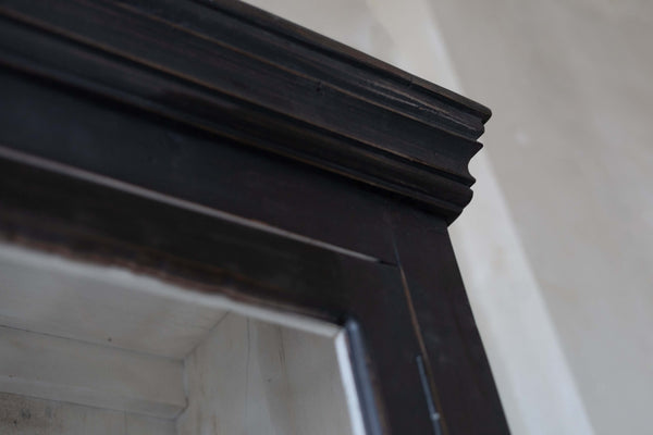 Close-up of wooden black hutch, showing crown moulding.