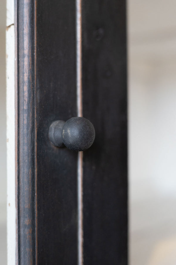 Close up detail of round knob of the black wooden hutch.