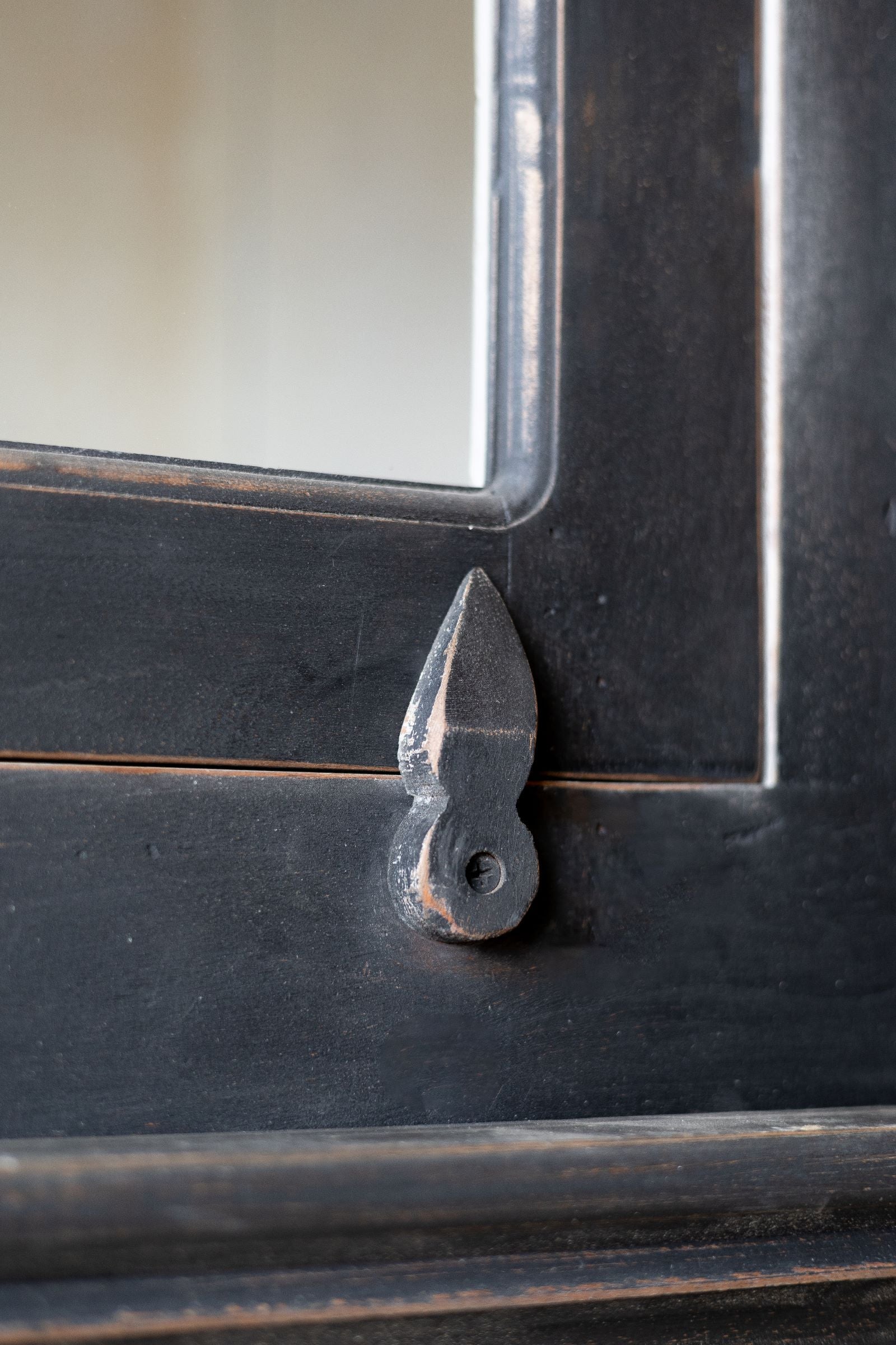 Close up detail of Latch holding door of the black wooden hutch closed.