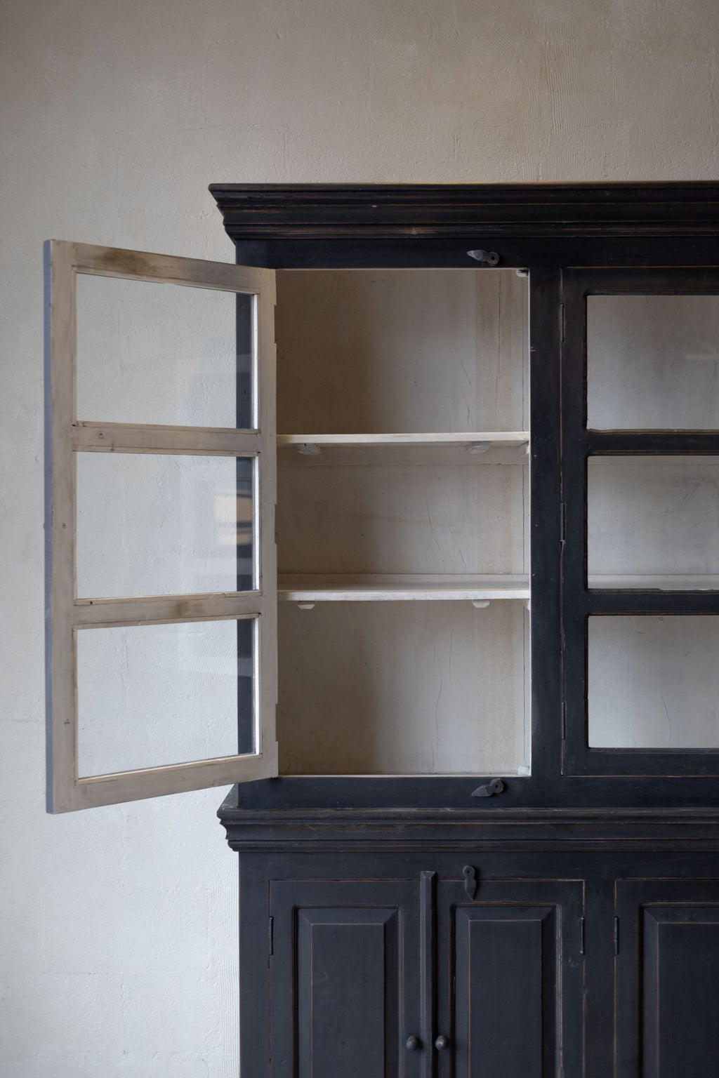 Left side of the black wooden hutch with top left cabinet door open revealing white interior of cabinet and door.