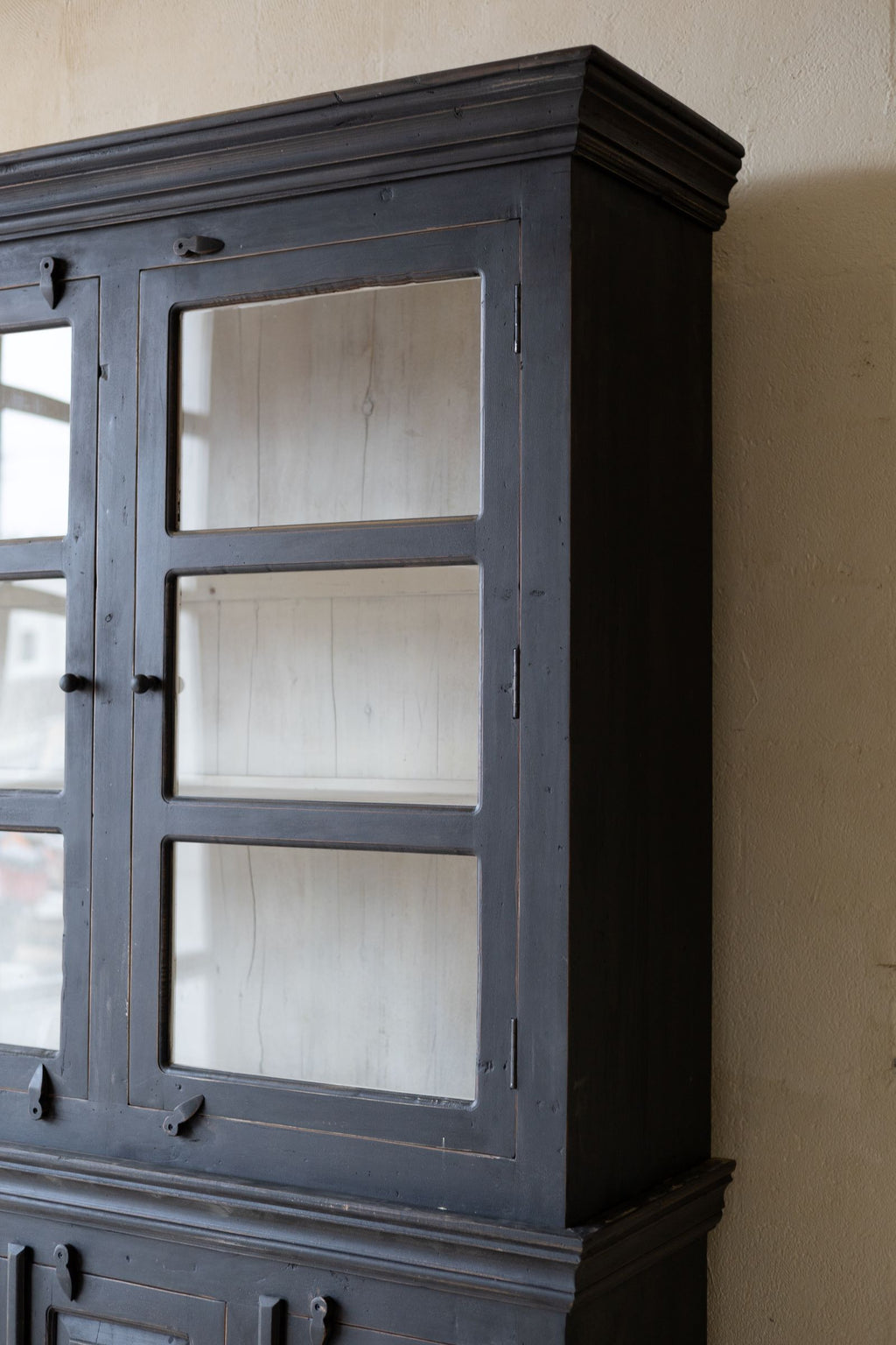 Top right side of black wooden hutch with door shut but glass windows showing the white interior. 