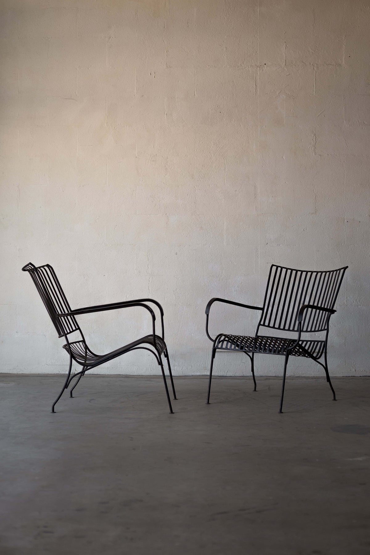 Two iron lounge chairs with vertical back slats and curved seats and armrests. Main image