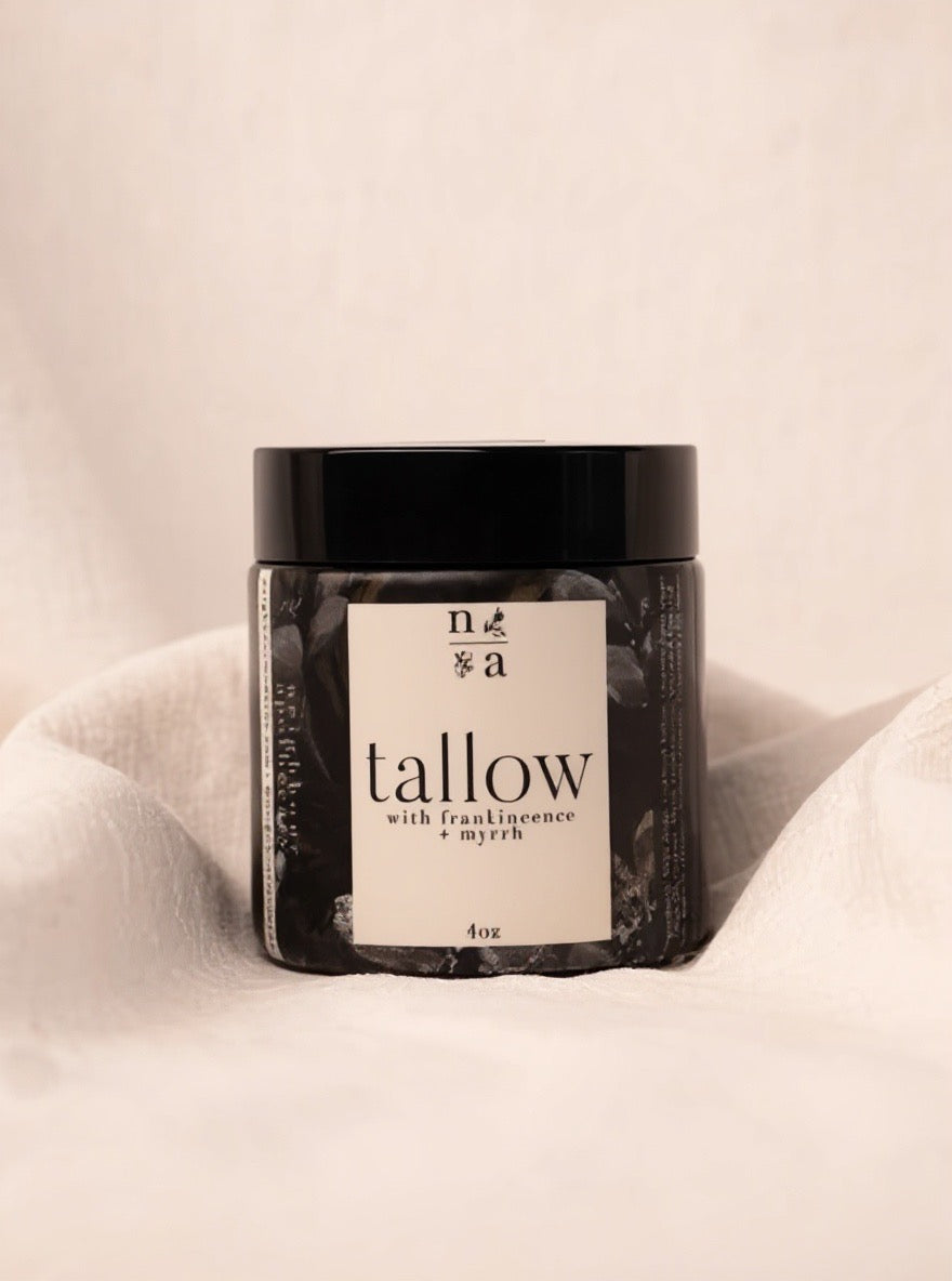 Jar of tallow body creme with a label on a beige background.