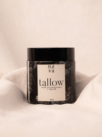 Jar of tallow body creme with a label on a beige background.