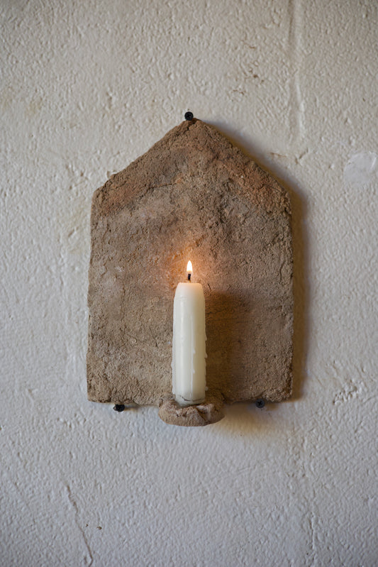 Candle in a stone holder on a textured white wall