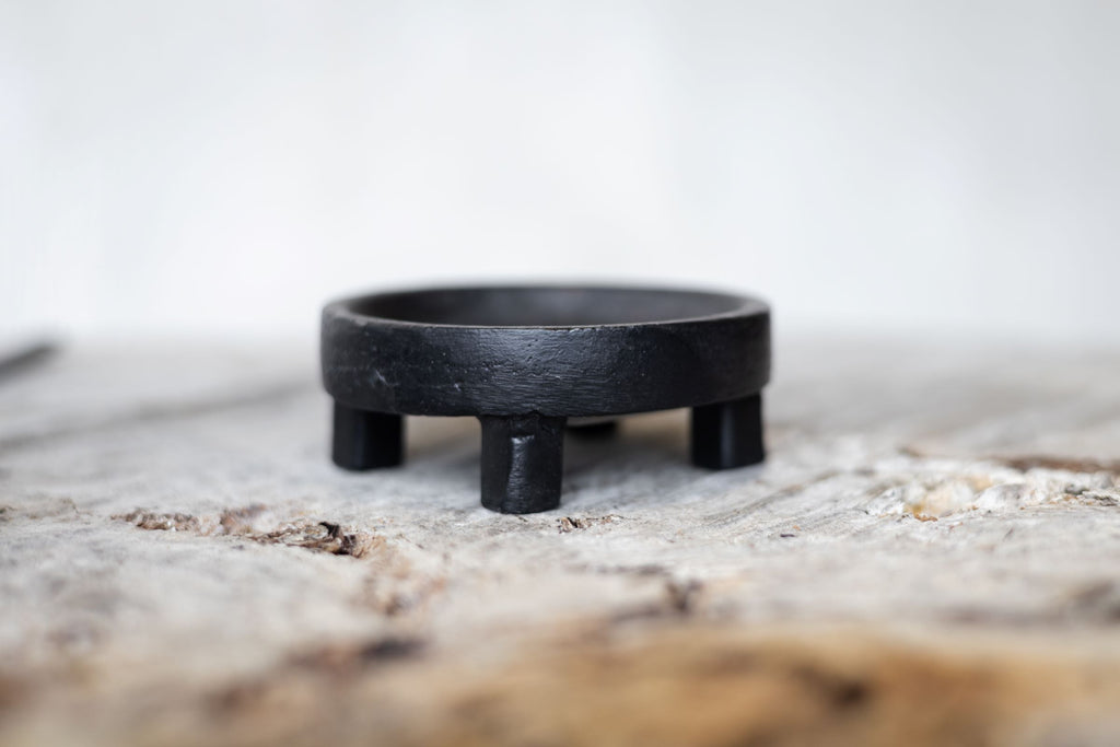 Close side view of round black iron salt holder.