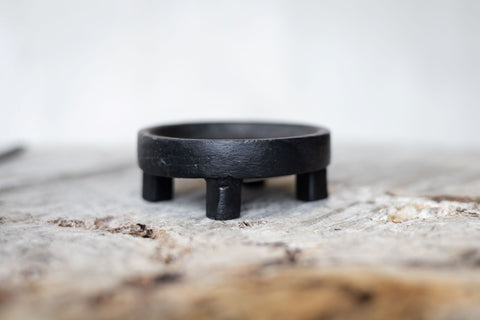 Close side view of round black iron salt holder.