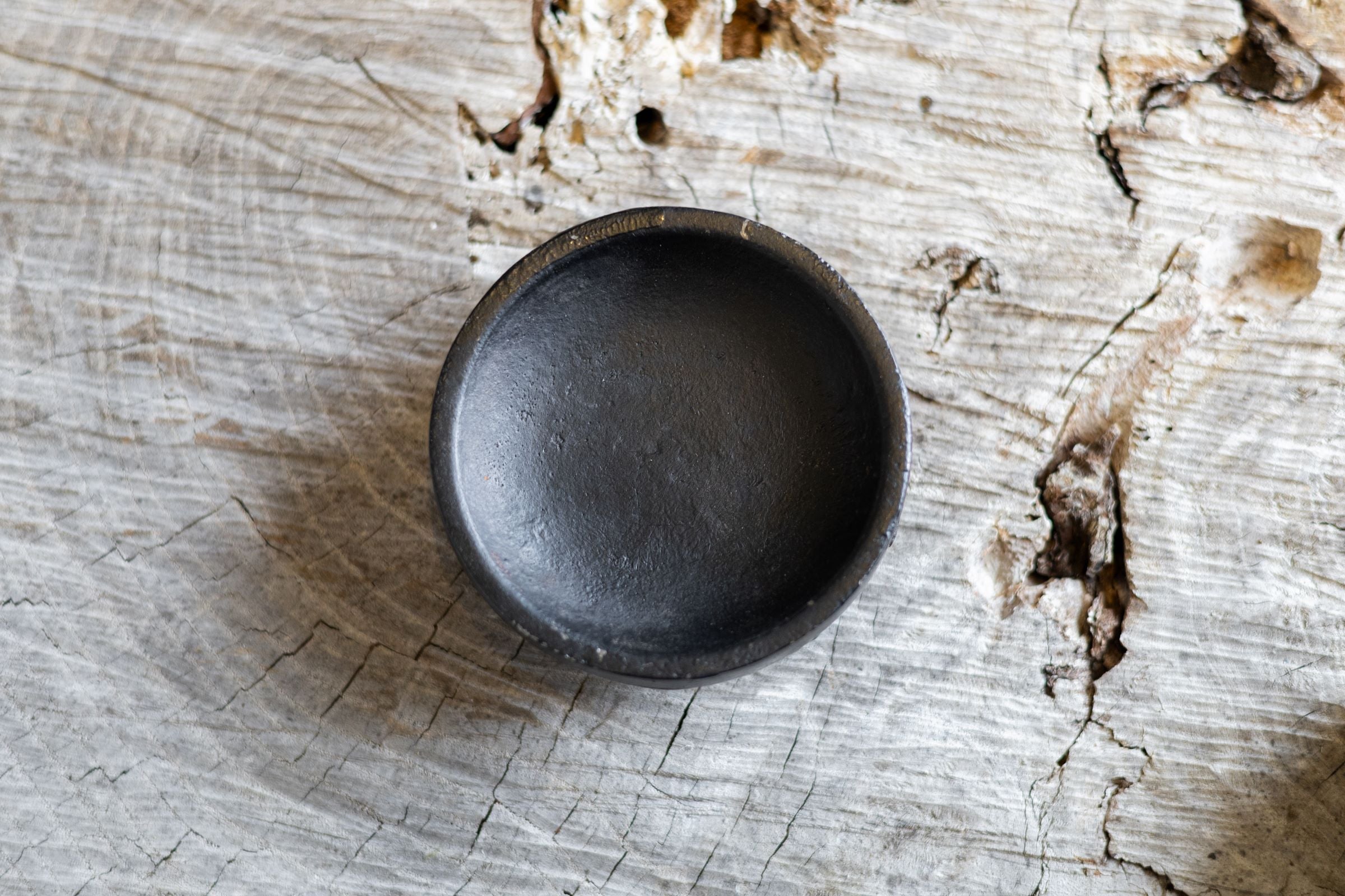 Overhead view of round black iron salt holder. 