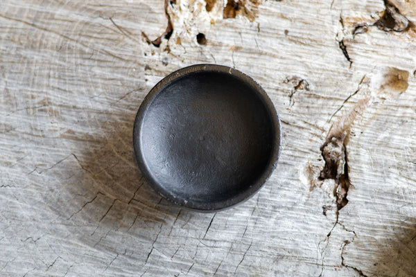 Overhead view of round black iron salt holder. 