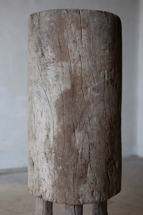 Butcher block table constructed out of a long tree stump with three rustic wooden legs. 