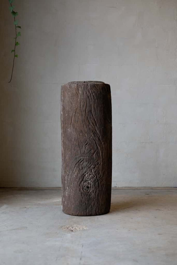 Butcher block table constructed out of a waist-high stump of dark brown wood.