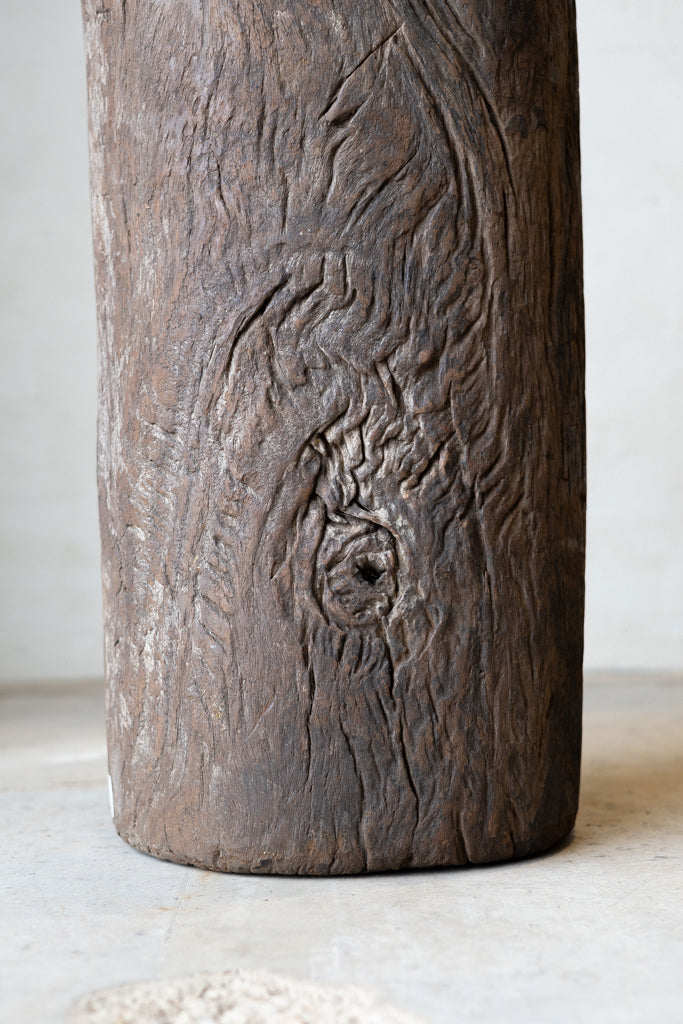 Close up of wood texture of butcher block table constructed out of a stump of dark brown teak wood.