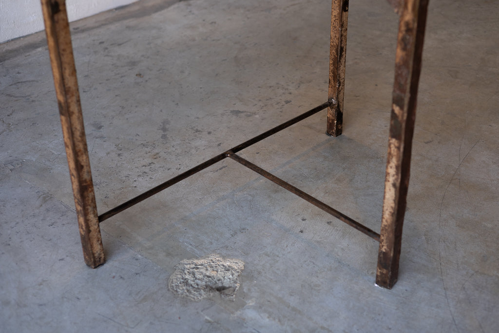 Legs of the Vienna triangle table featuring rustic patina and horizontal bars for stability.
