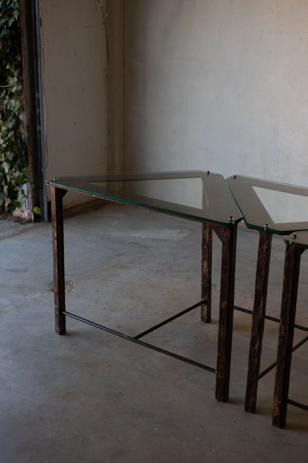 Triangular glass-top side tables with iron frames. 