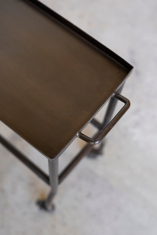 Metal table with a brown top on a concrete floor