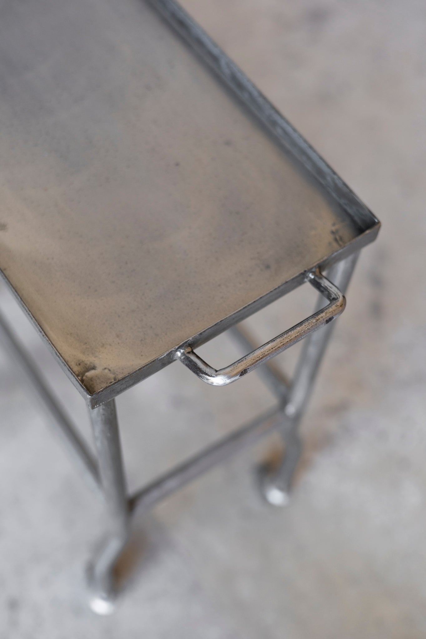 Metal stool with a worn surface on a concrete floor