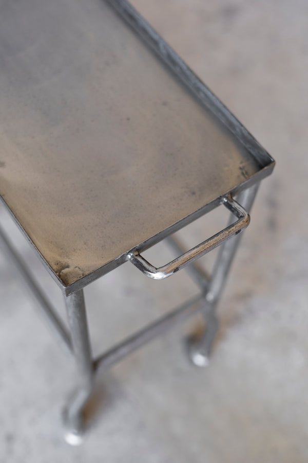 Metal stool with a worn surface on a concrete floor