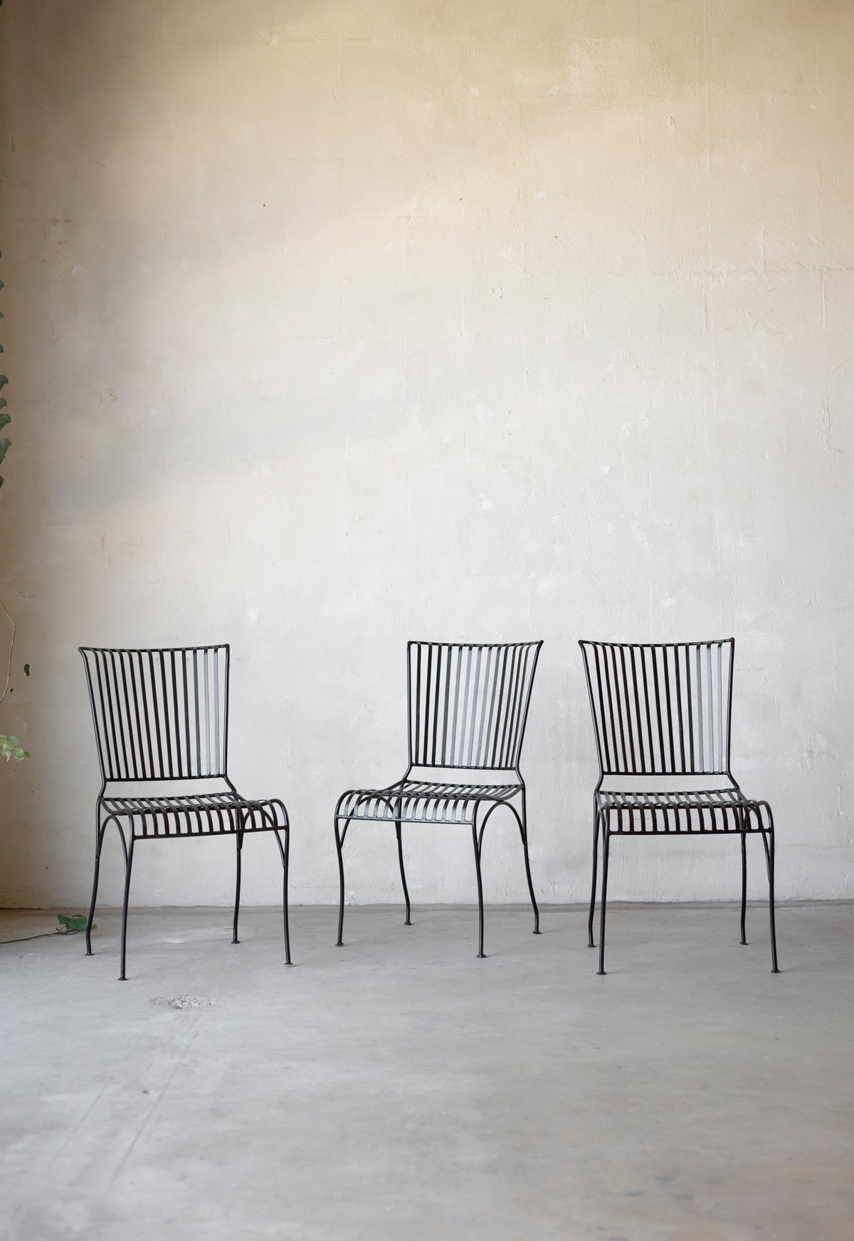 Three black metal chairs against a plain wall. Main image